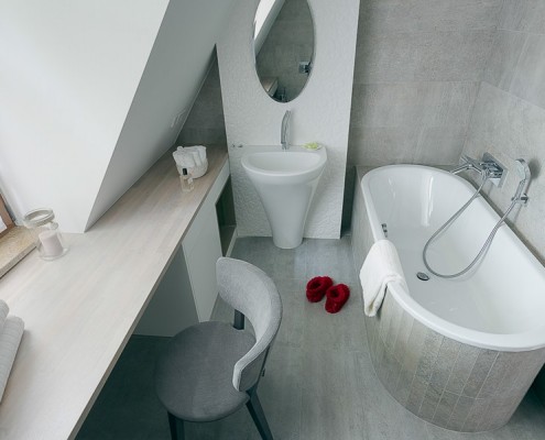 Aranżacja szarej łazienki z toaletką na poddaszu