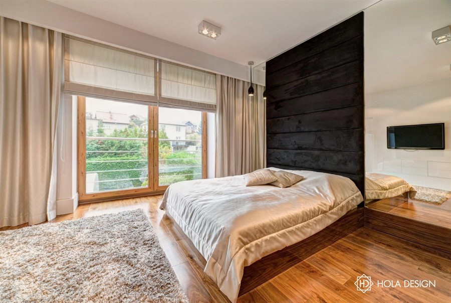 Piękna sypialnia z tapicerowaną ścianą szykowny minimalizm