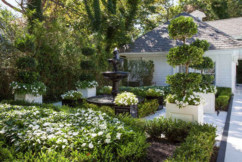 Zielony ogród z klasycznymi donicami i fontanną
