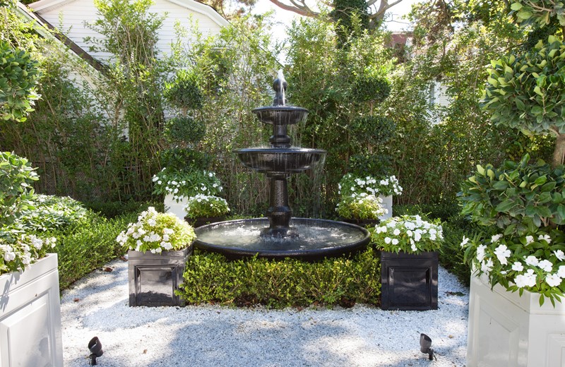 Zielony ogród z klasycznymi donicami i fontanną
